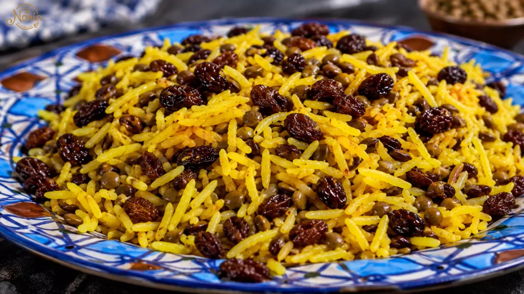 Persian lentil rice with golden saffron basmati rice, brown lentils and dark raisins, served on a decorative blue and white ceramic plate.