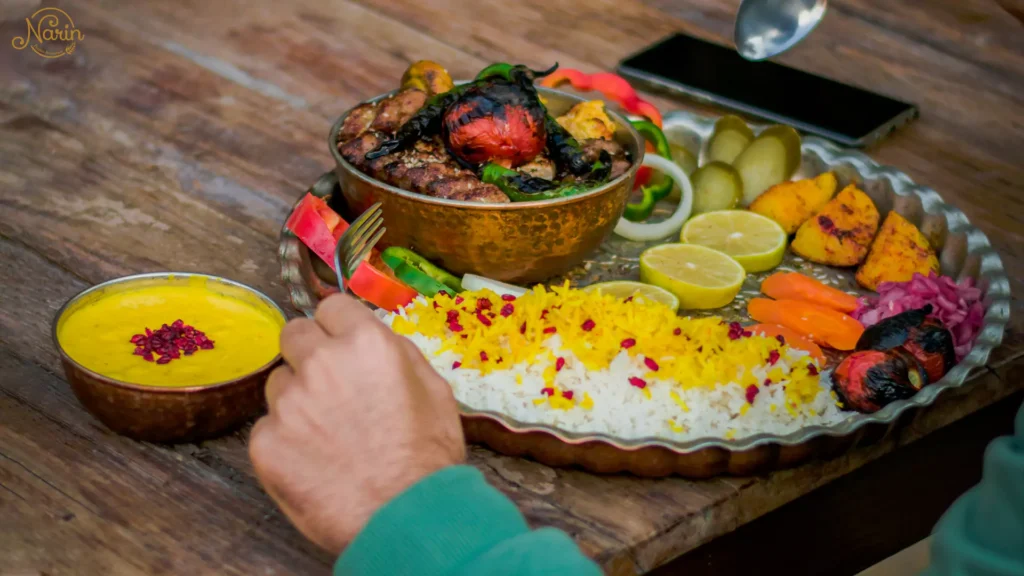 A person enjoying a traditional meal at Narin, the best persian restaurant in northmead, featuring a copper bowl of gas-grilled kebabs, saffron rice with barberries, and fresh sides on a rustic wooden table.