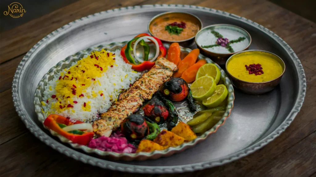 A silver tray of gas-grilled chicken kebab with saffron rice, grilled tomatoes, and traditional dips at Narin, the best persian restaurant in northmead.   