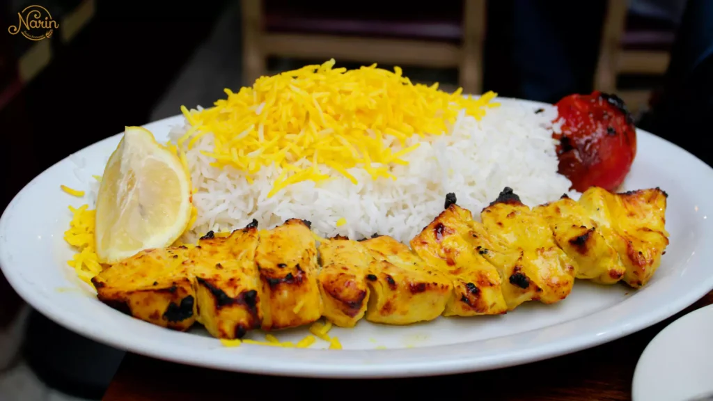 A plate of gas-grilled chicken kebab (Joojeh) with saffron rice and grilled tomato at Narin, the best persian restaurant in northmead.   