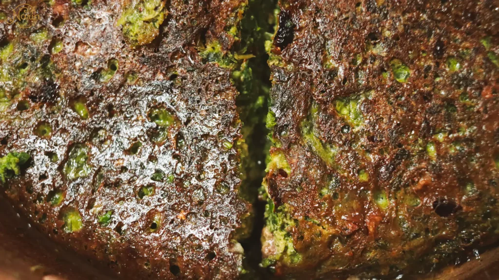 Extreme close-up of authentic Persian Kuku Sabzi, a traditional vegetarian fresh herb frittata featuring a crispy pan-fried crust and a vibrant green interior, prepared at Narin Persian Restaurant in Sydney.