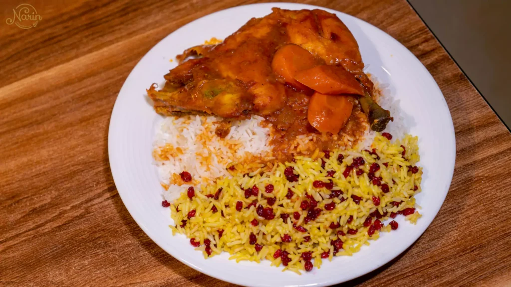 Classic Zereshk Polo ba Morgh with slow-cooked chicken, carrots, and saffron rice mixed with tart barberries.