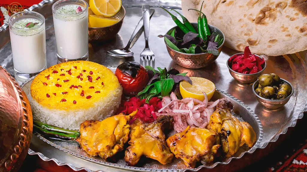A magnificent silver platter of gas-grilled bone-in chicken kebab with saffron rice and Doogh, showcasing exactly what to order at a Persian restaurant like Narin.   